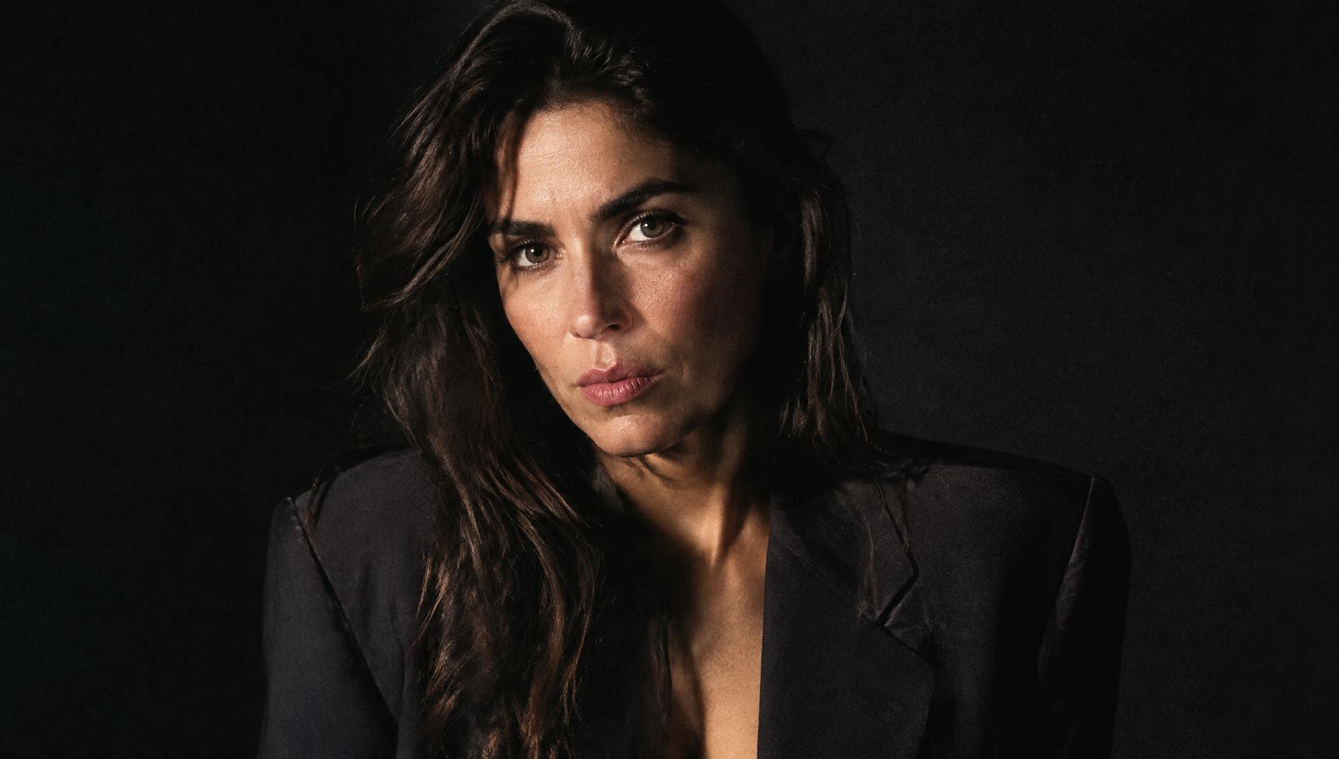 Retrato de una mujer con americana oscura, iluminada lateralmente sobre fondo negro